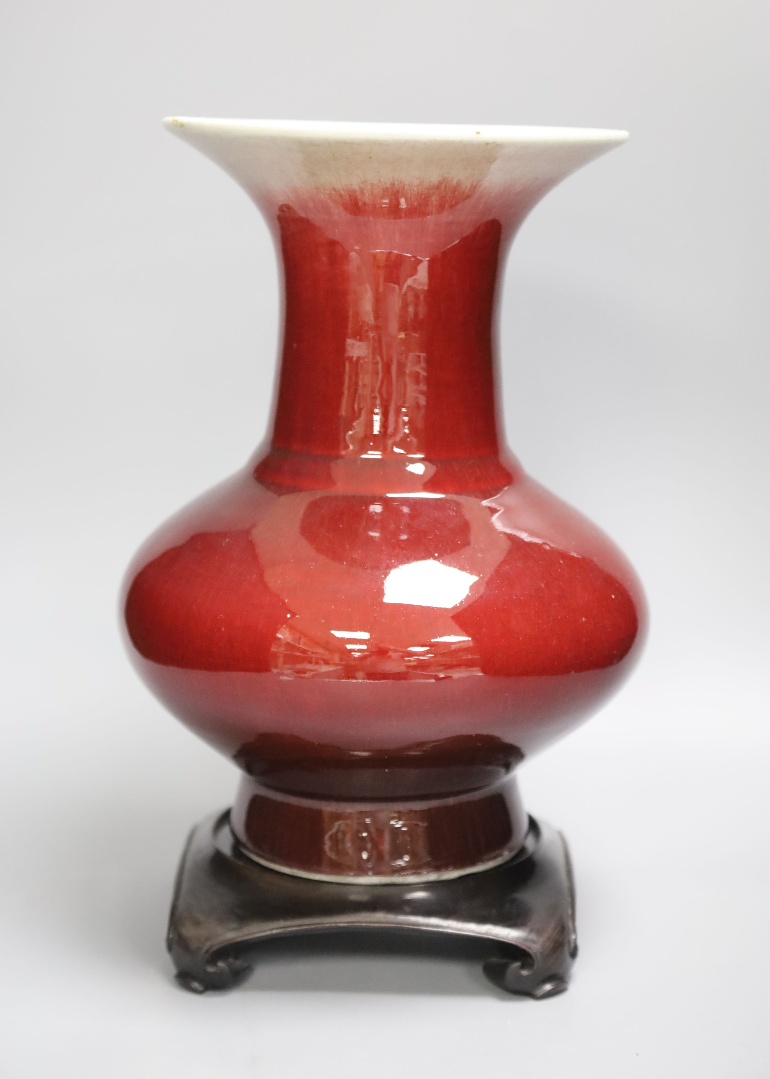 A 19th century Chinese sang de boeuf vase of squat baluster form with everted rim (a.f.), on square hardwood stand, overall height 35.5